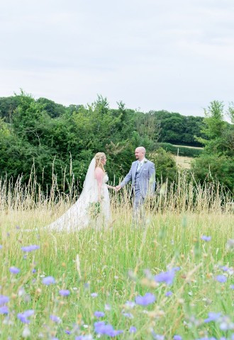 Bride and Groom on the wildflower meadow, Monkton Barn