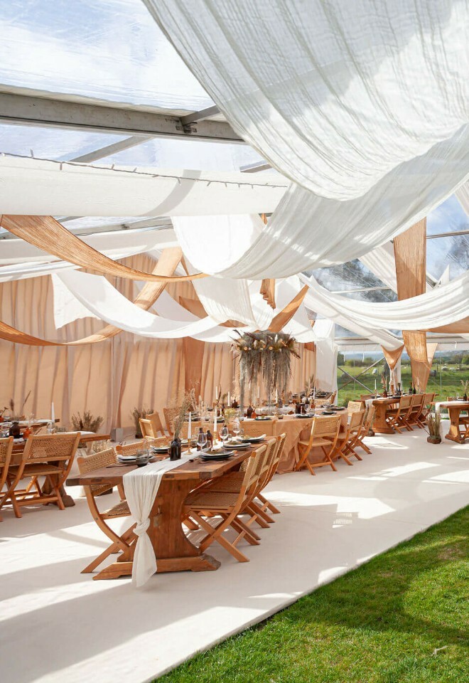 White and brown muslin draping hanging over banquet dining tables in a clearspan marquee