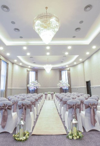 Ballroom set for a ceremony with chair covers and sashes