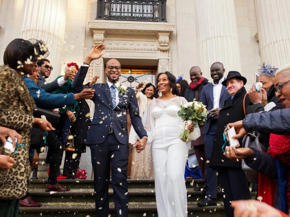 Bride and groom walking down the steps of Old Marylebone Town Hall in London as guests throw confetti outside the ceremony venue