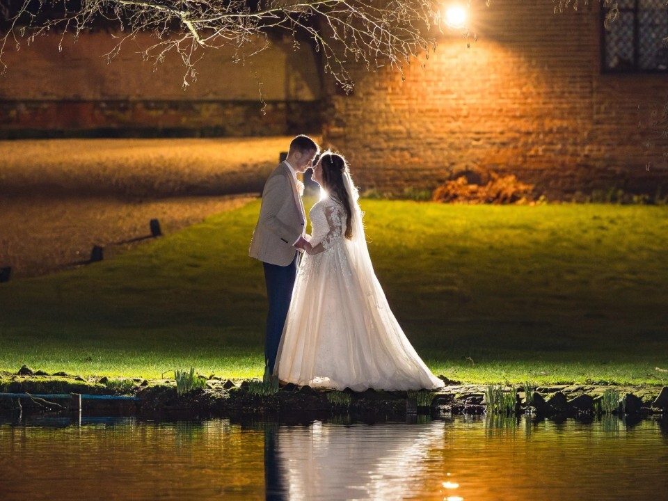 A couple photographed in the dark by a river with a light on them
