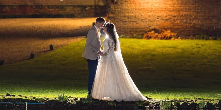 A couple photographed in the dark by a river with a light on them