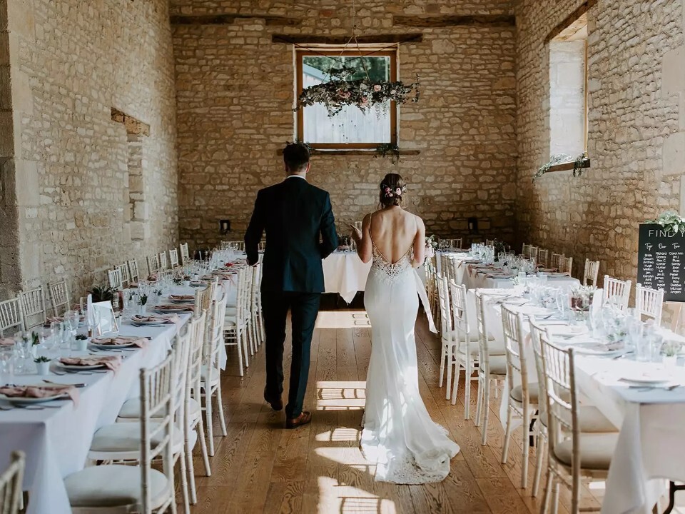 Bride and groom view their wedding breakfast set up at a no corkage wedding venue, The Barn at Upcote