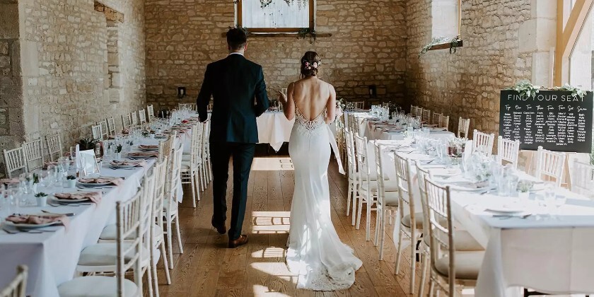 Bride and groom view their wedding breakfast set up at a no corkage wedding venue, The Barn at Upcote