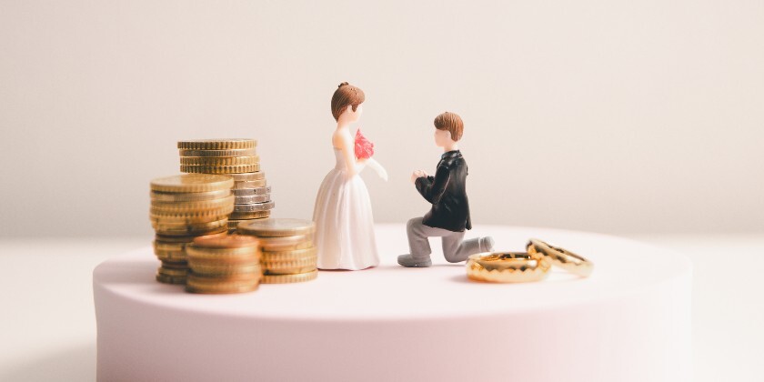 Models of a bride and groom next to coins and wedding rings