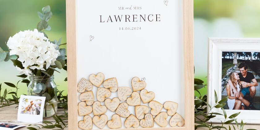 see through box framed with wooden hearts inserted inside with wedding guest signatures and phots of the couple surrounding the frame