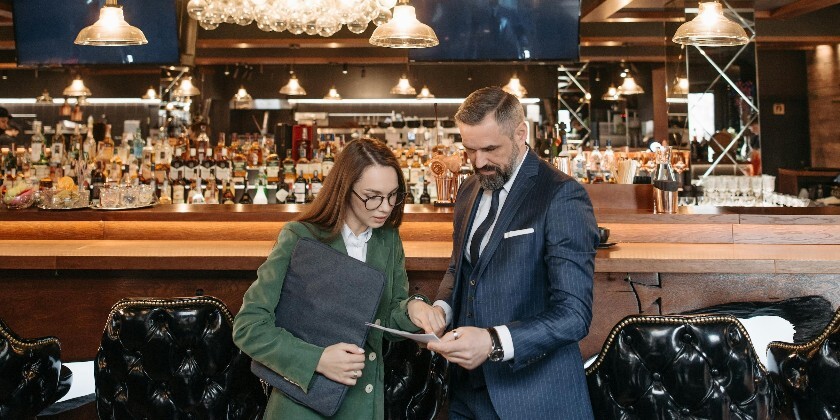 General manager of wedding venue with team member looking at paperwork next to the venues bar