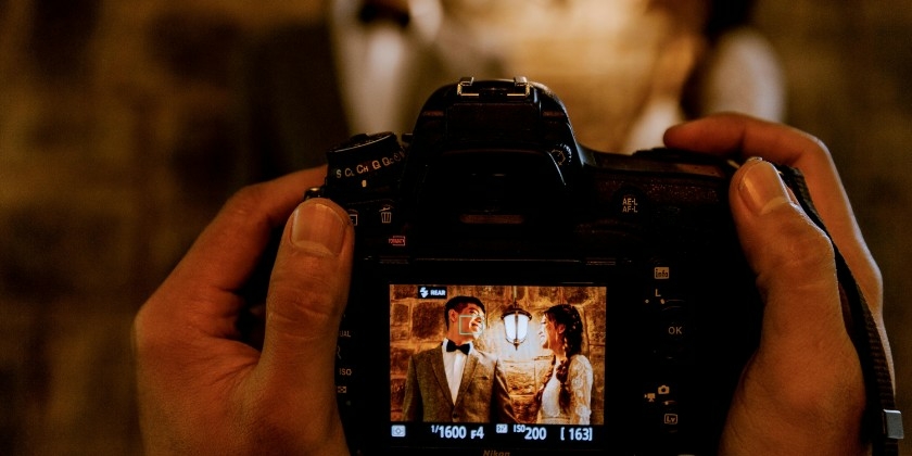 Wedding photographer holding a camera with the screen showing a bride and groom posing.