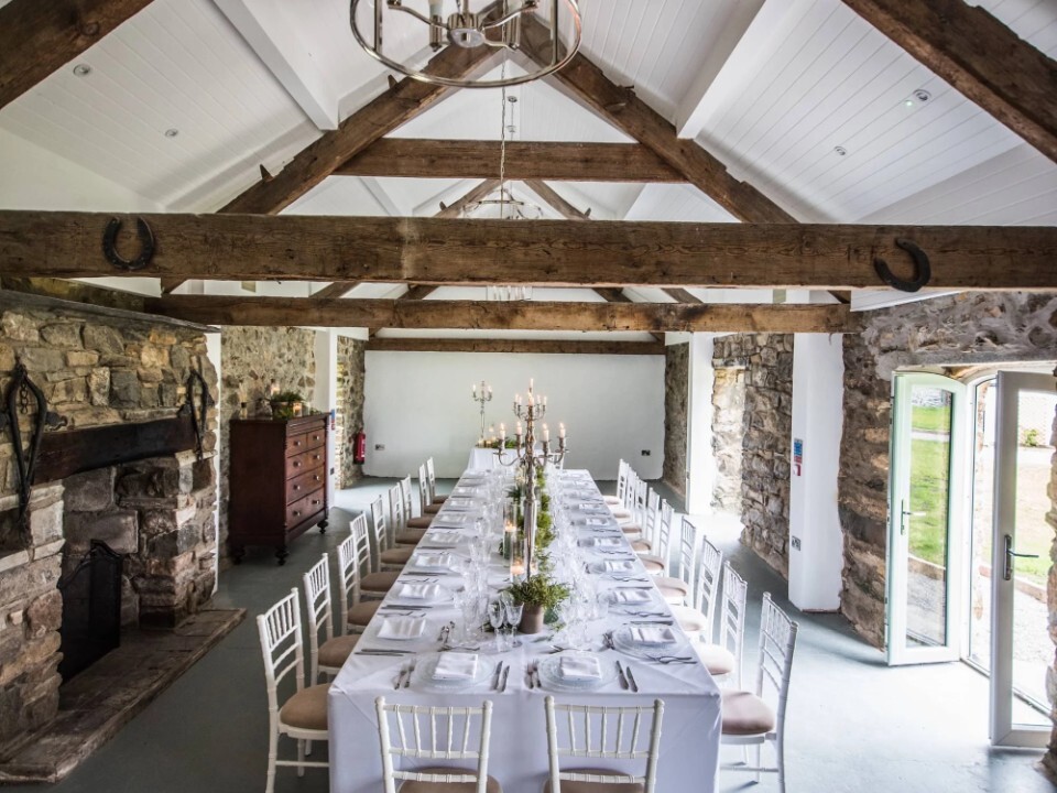 Reception area inside a Barn venue with tables and flower decor
