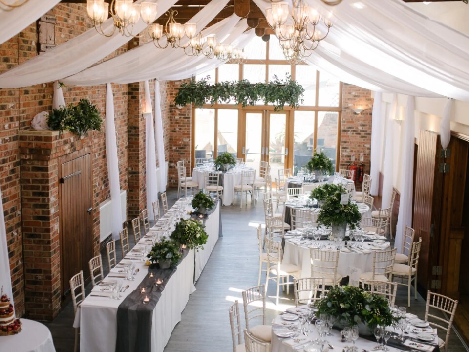 Inside of barn venue that is decorated with tables and sheet bunting.