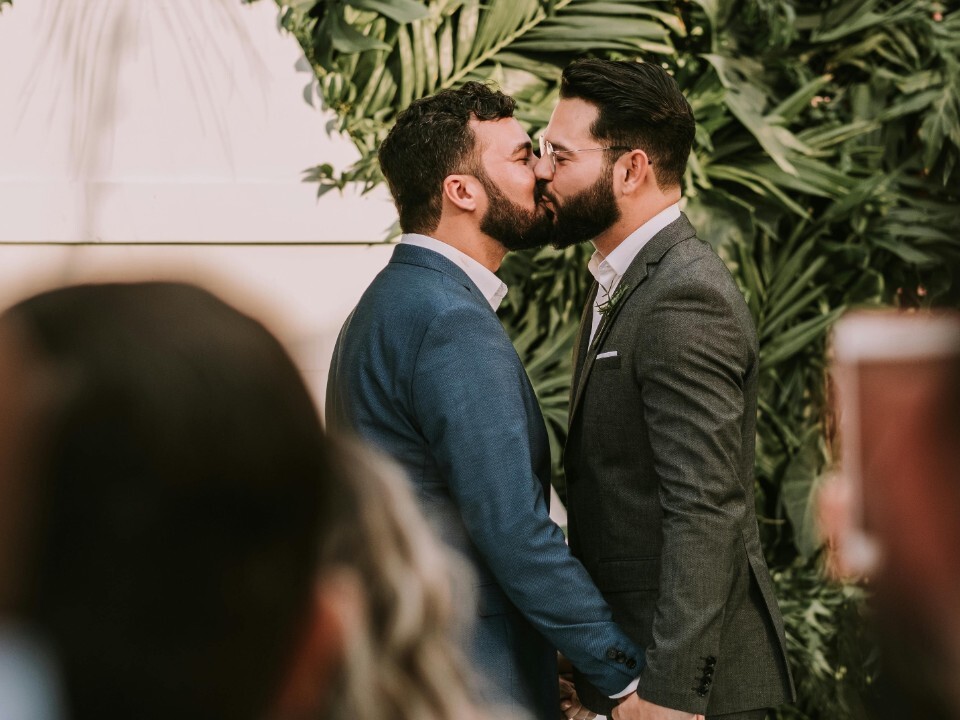 Groom and groom kiss at the alter on their wedding day