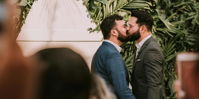 Groom and groom kiss at the alter on their wedding day