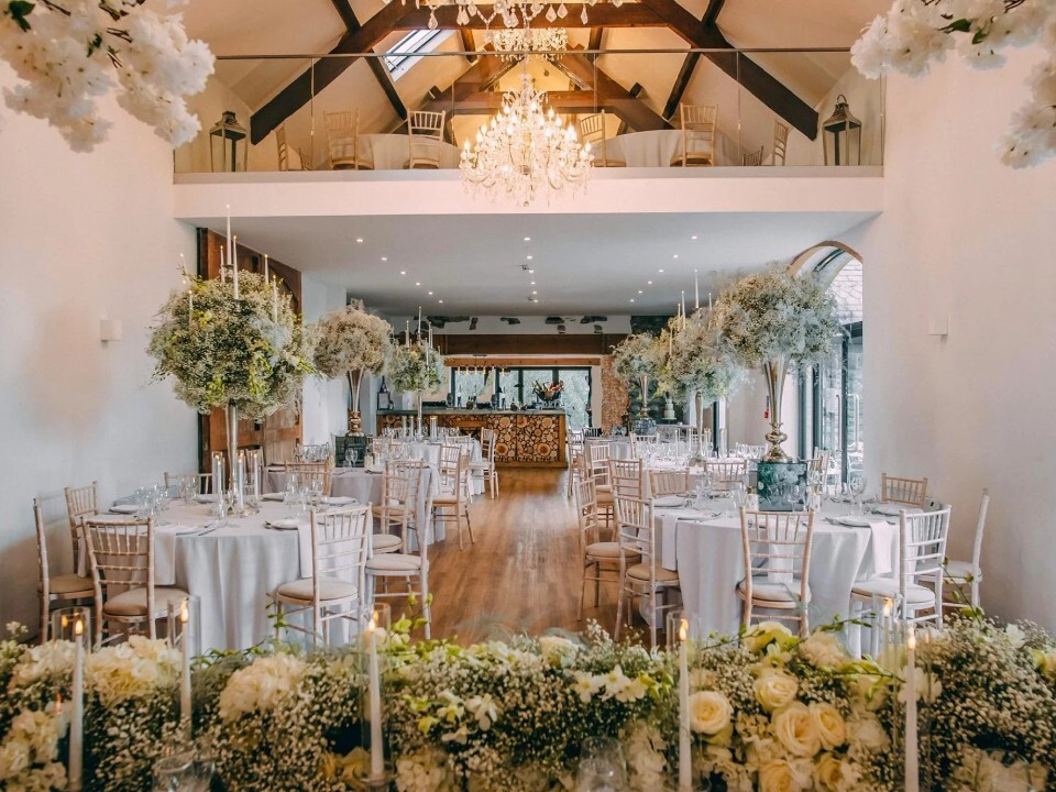Reception area inside a Barn venue with tables and flower decor
