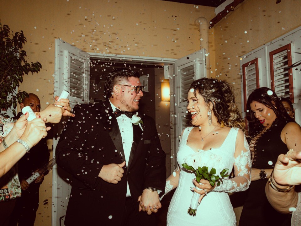 Bride and groom having confetti thrown over them - they smile at each other