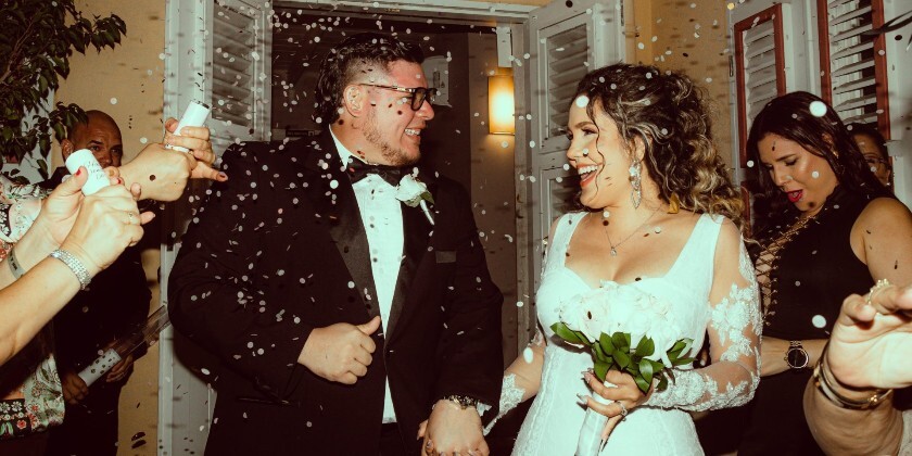 Bride and groom having confetti thrown over them - they smile at each other