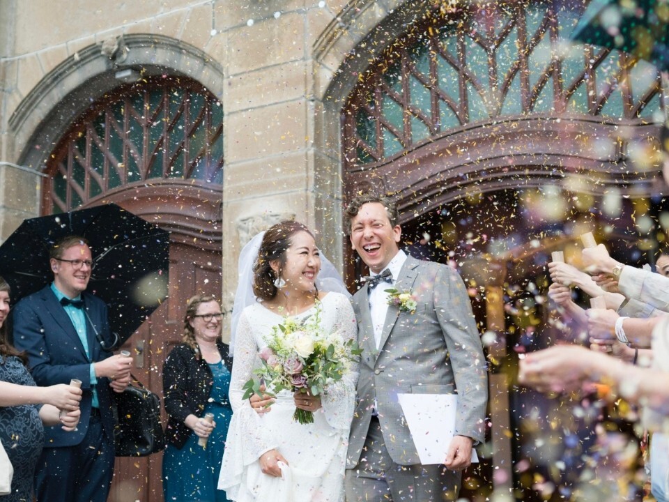 Wedding couple leaving their ceremony as guests throw dried petal confetti, creating a colourful confetti moment outside the venue