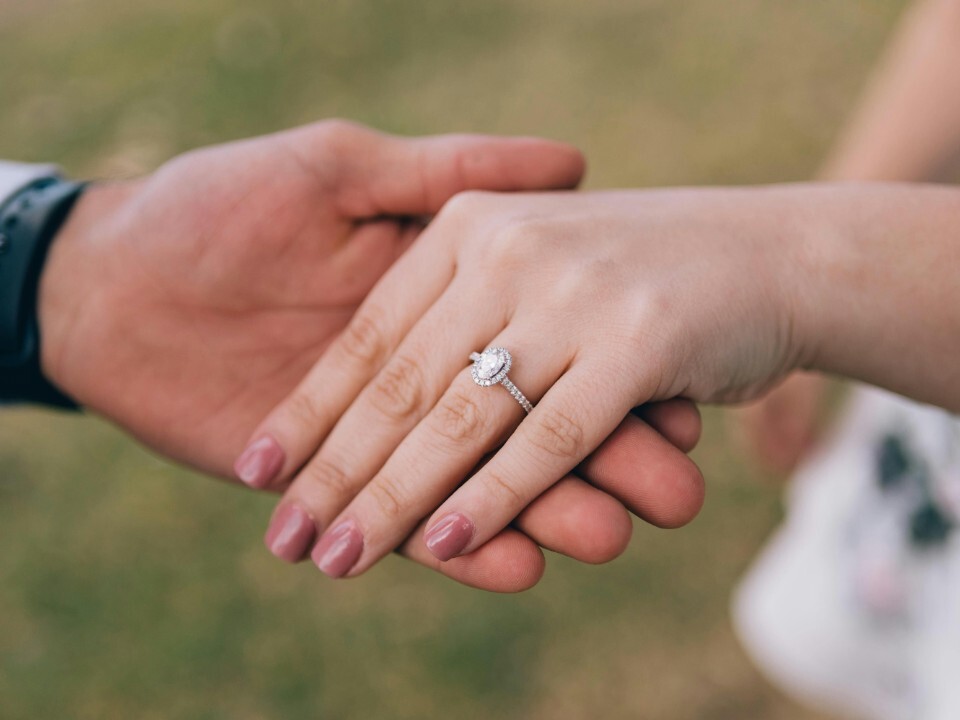 Close-up of couples hands holding with engagement ring