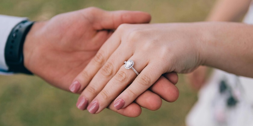 Close-up of couples hands holding with engagement ring