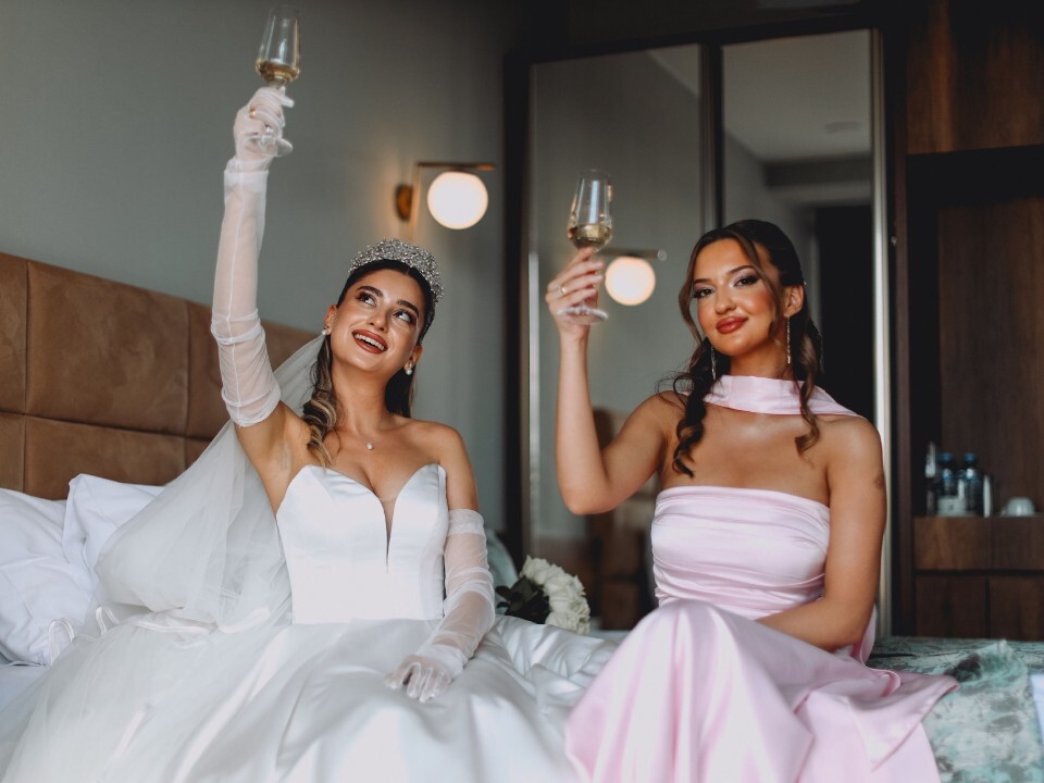 Bride and bridesmaid holding up champagne glasses ready for the wedding