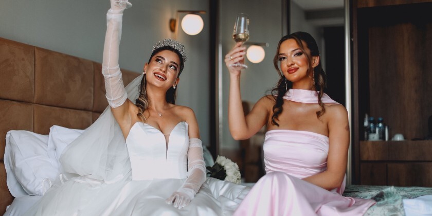 Bride and bridesmaid holding up champagne glasses ready for the wedding