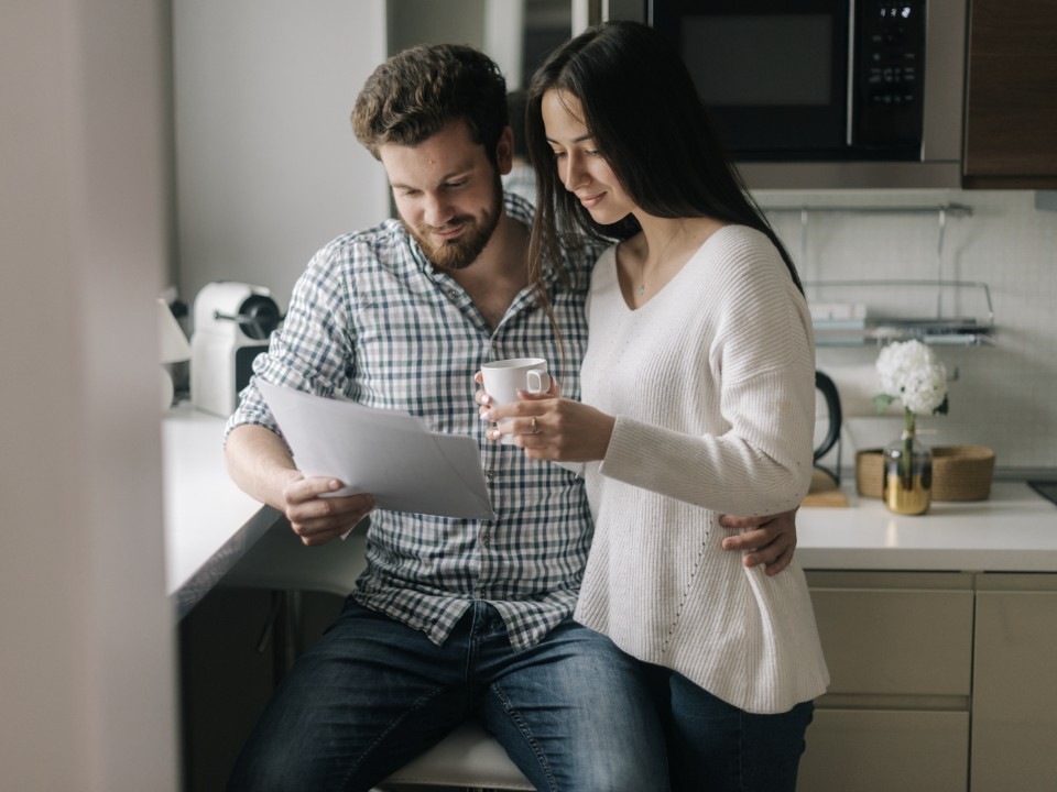 A couple reading a document together in the kitchen
