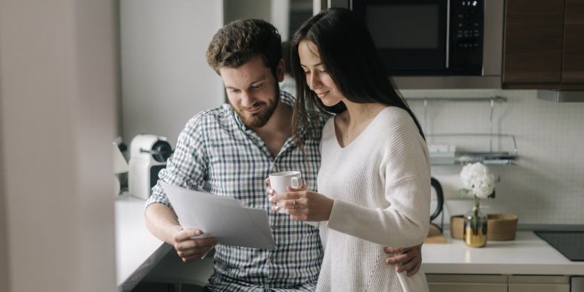 A couple reading a document together in the kitchen