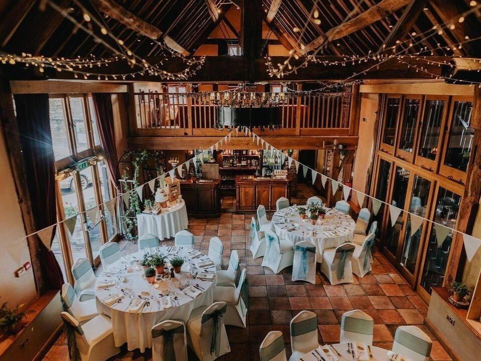 Inside of barn venue that is decorated with tables and bunting.