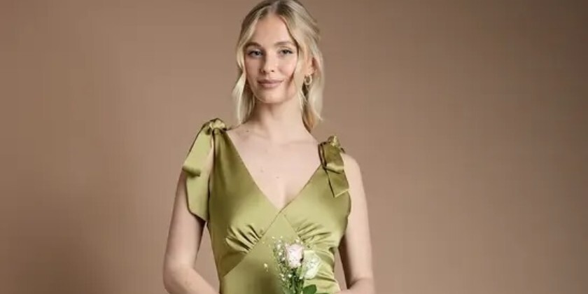 Teen bridesmaid wearing an olive green satin maxi bridesmaid dress with tie shoulder straps and a V-neckline.