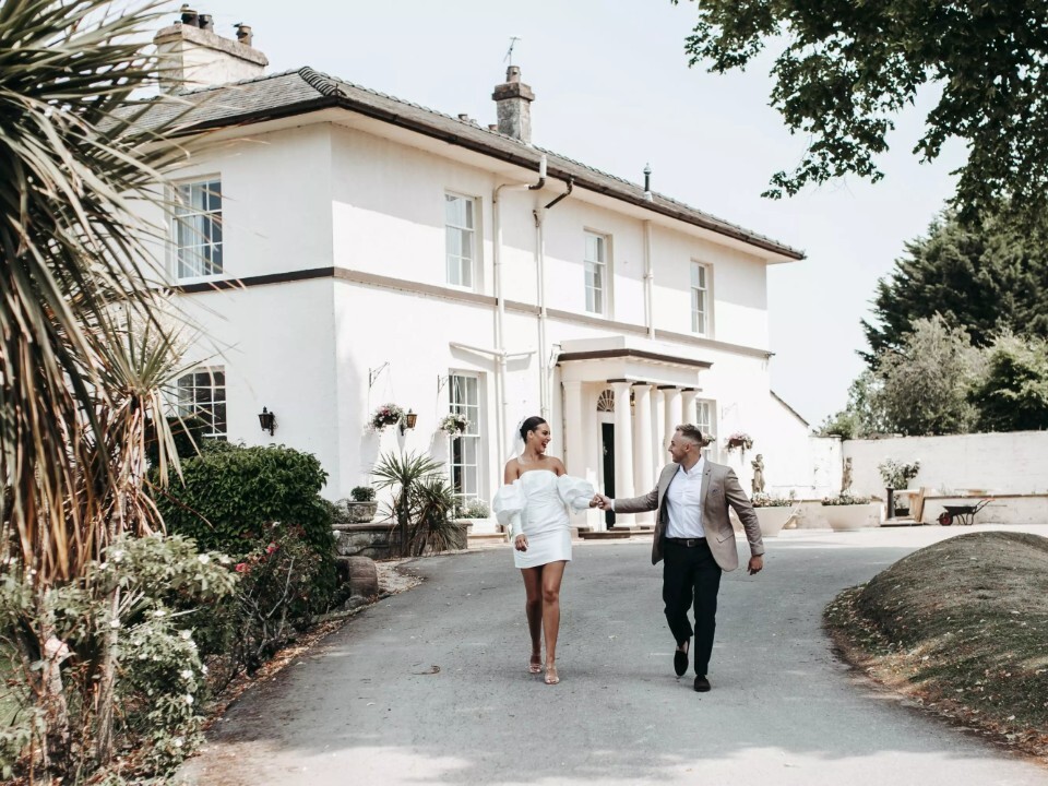 Bride and groom walking in front of their wedding venue in Wales