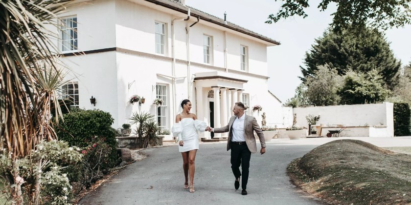 Bride and groom walking in front of their wedding venue in Wales