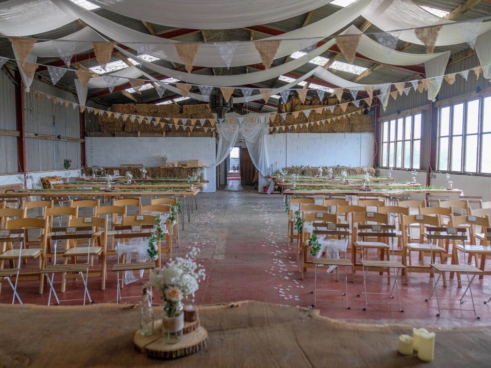 Ceremony area in inside of barn venue with bunting