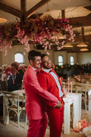 two men in pink and red suits hugging each other smiling