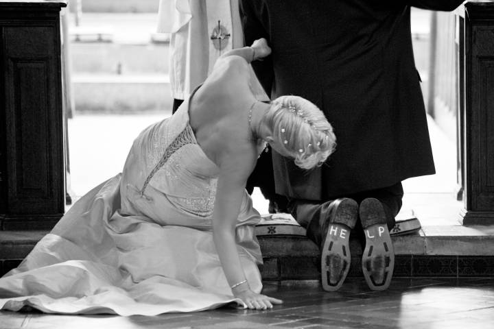 Groom kneeling with HELP written on soles of shoes