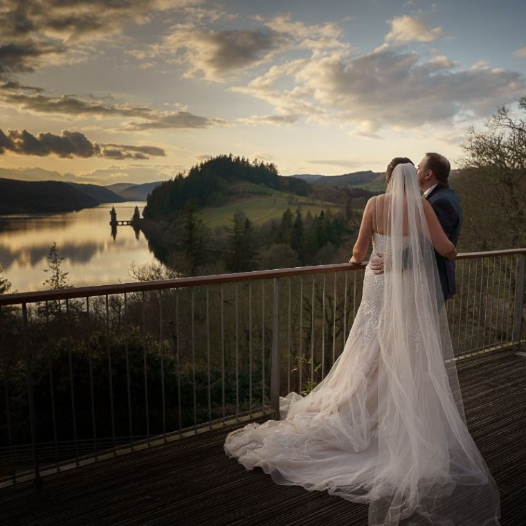 A bride and groom, looking over Lake Vyrnwy from the balcony of the Hotel