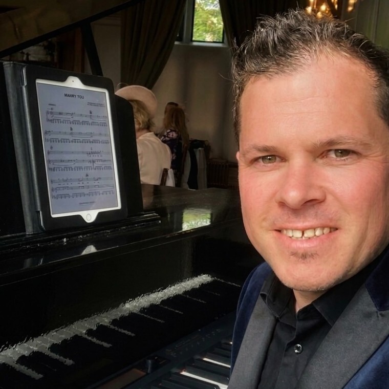 Award winning Cheshire wedding pianist Chris Morris, in a dark blue tuxedo jacket, playing his grand piano at the Maynard