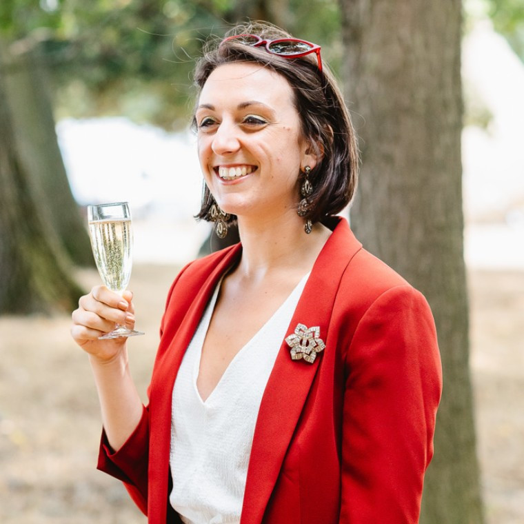 evie the celebrant smiling with a glass of fizz in hand
