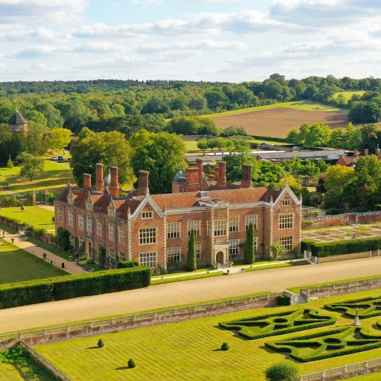 Aerial view of North Mymms Park, a historic red-brick wedding and events venue surrounded by formal gardens, landscaped grounds and rolling Hertfordshire countryside.