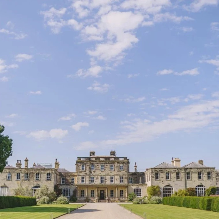 Grand estate with manicured lawns and bright blue sky