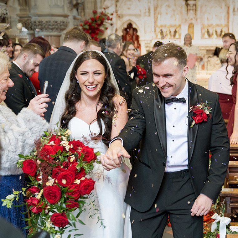 Confetti being throw as bride and groom walk down aisle 