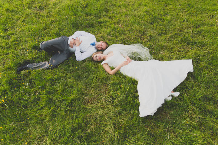 Bride and groom laying in the sun on their wedding day. Unique wedding photography and videography b