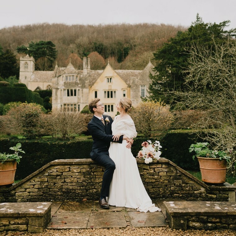 Bride and Groom looking at eachother with Owlpen Manor in the background taken by Greenhill Wedding Photography