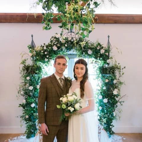 Couple Standing In Front of Floral Arch at Cotswold House Hotel and Spa, Venues in Chipping Campden, Gloucestershire