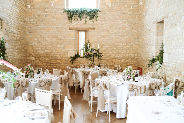 Round tables set for a rustic wedding breakfast at The Barn at Upcote