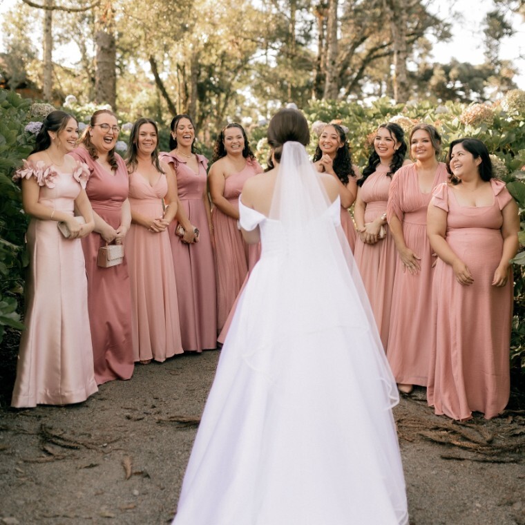 Bride looking at her bridesmaids in pink bridesmaid dresses