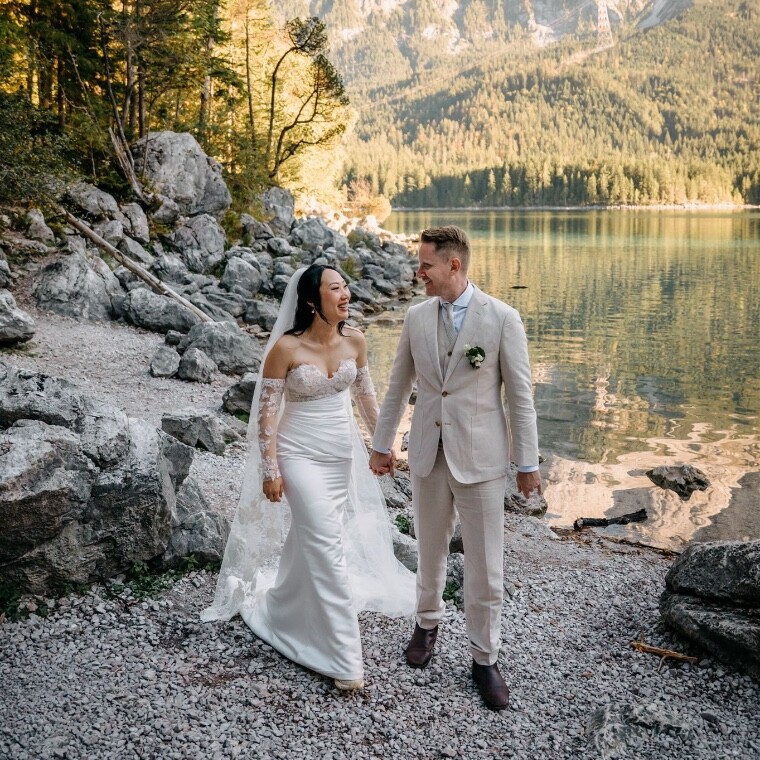 Bride and groom walking hand in hand next to a Bavarian lakeside 