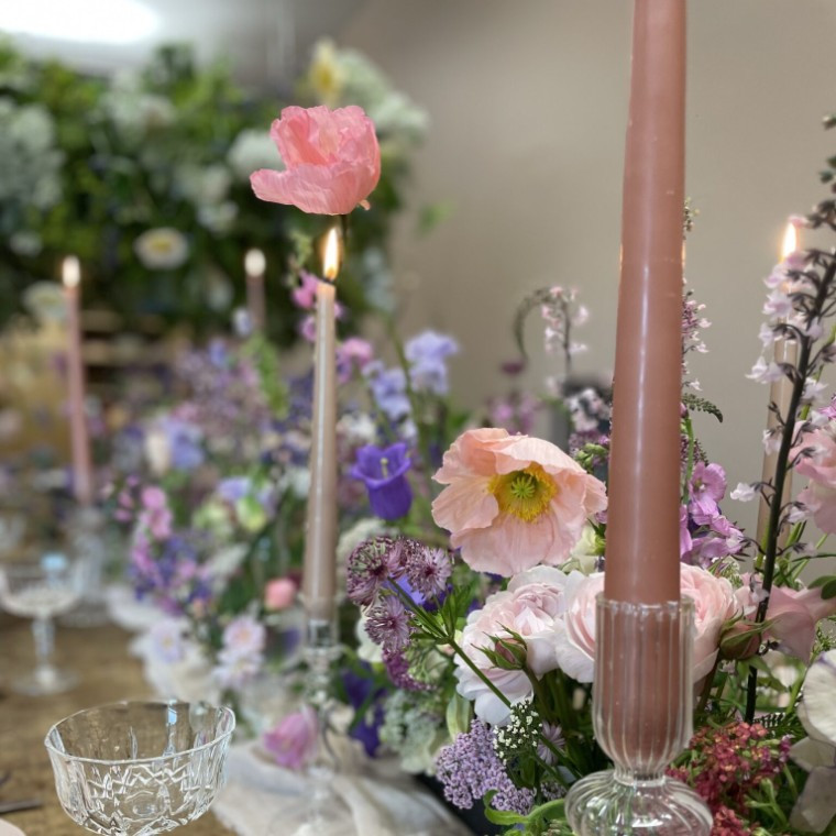 Wild Fig Flowers wedding table arrangement in Oxfordshire, featuring pink, purple and white seasonal flowers with elegant pink candles and glassware.