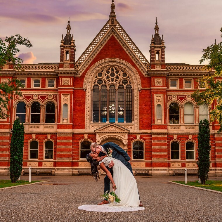 A wedding couple, embraced, in front of Dulwich College at golden hour.