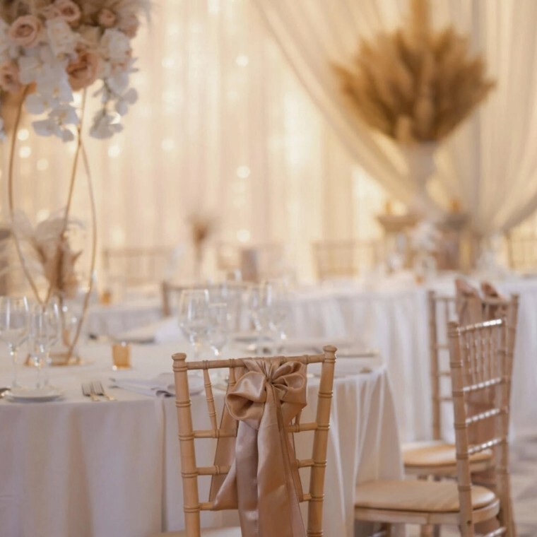 Wedding table with wooden chairs and pampass grass centre pieces on white table clothes.
