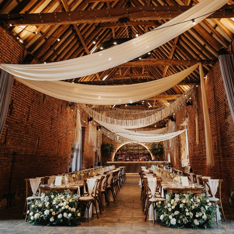 Interior of Copdock Hall barn with draping and long tables set for a wedding