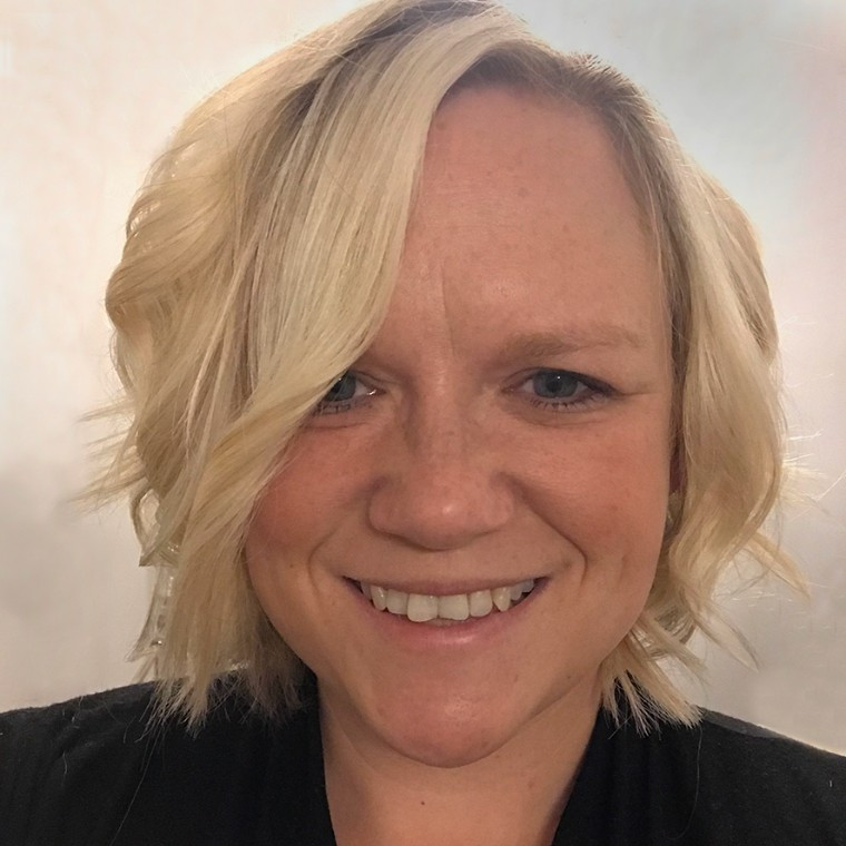 Woman in her 40s with blonde curls smiling into the camera